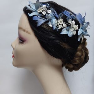 Tocado para invitada de boda con flores y plumas azules, vista lateral.