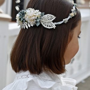 Corona de flores artesanal con tonos verde agua, blancas y detalles de hojas decorativas, perfecta para eventos especiales.