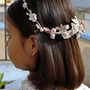 Corona de flores hecha a mano en tonos rosa empolvado y blanco, con detalles de hojas doradas y flores delicadas, ideal para eventos elegantes.