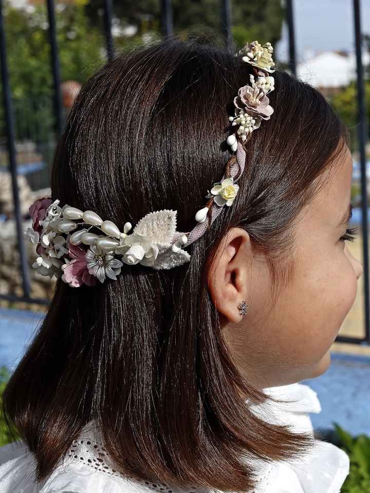 Corona de comunión modelo Mérida, de color rosa y adornada con perlas blancas brillantes, perfecta para un look elegante en el día de la comunión.