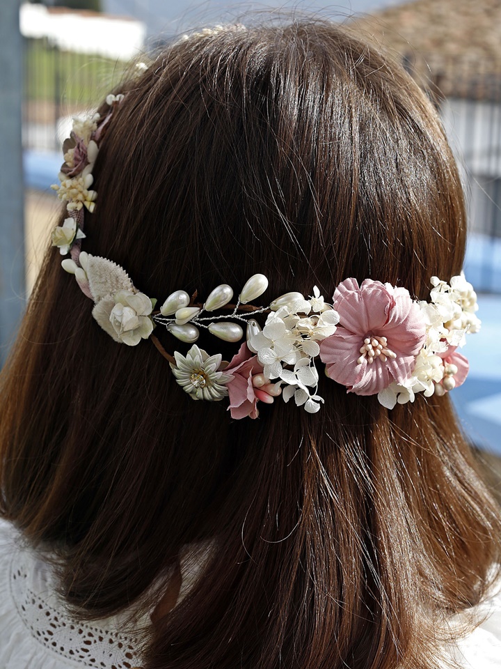 Corona de comunión modelo Mérida, de color rosa y adornada con perlas blancas brillantes, perfecta para un look elegante en el día de la comunión.