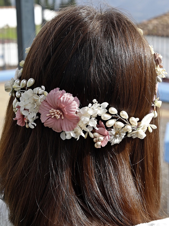 Corona de comunión modelo Mérida, de color rosa y adornada con perlas blancas brillantes, perfecta para un look elegante en el día de la comunión.